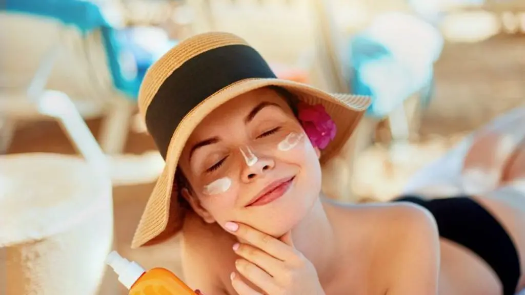 Donna che applica crema solare sul viso in una giornata soleggiata, simbolo di protezione SPF 50 contro i raggi UV