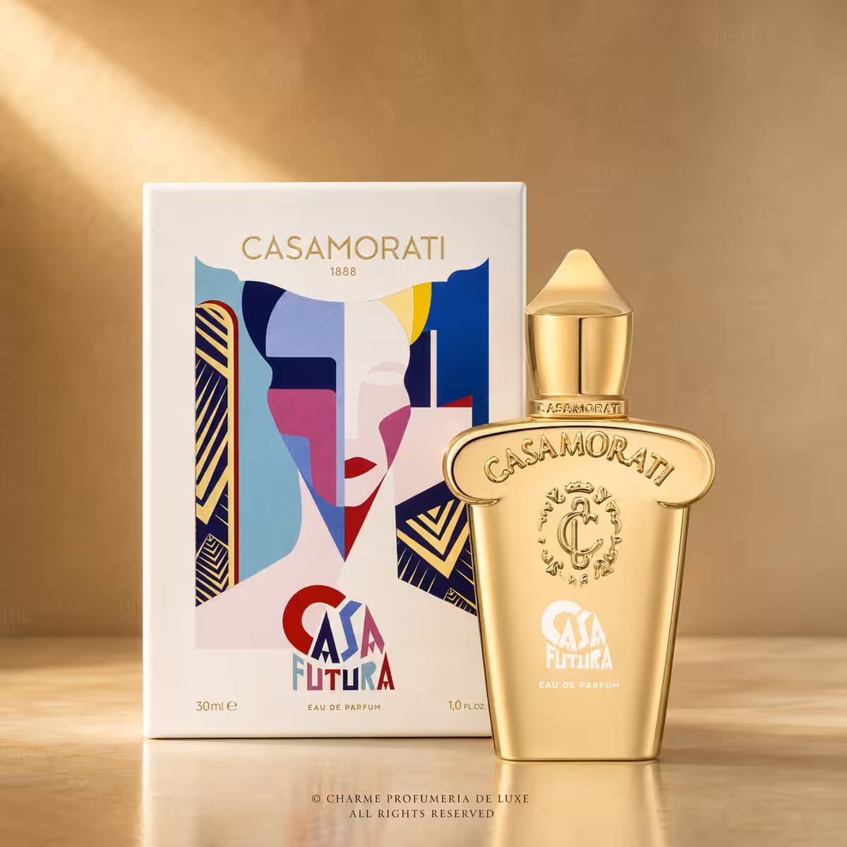 Gold Casamorati perfume bottle with colorful abstract box art beside it on a warm backdrop.