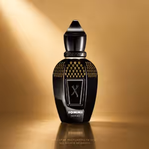 Black perfume bottle with gold skull studs and an angular cap, standing on a reflective gold surface with 'XERJOFF IOMMI DEIFIED' branding.