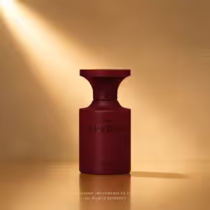 Maroon perfume bottle labeled Black Guava on a warm, amber backdrop with soft spotlight.