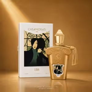 Gold Casamorati Lira perfume bottle with tassel next to its white box featuring Art Nouveau artwork.