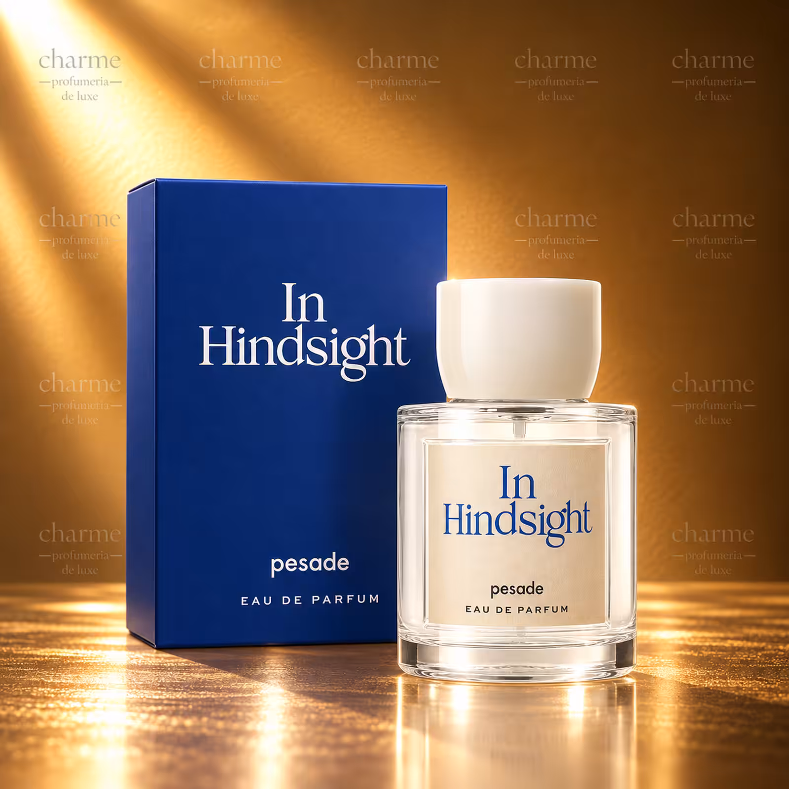 Pesade In Hindsight Eau de Parfum, flacone in vetro trasparente con tappo avorio e confezione blu scuro coordinata su sfondo dorato.